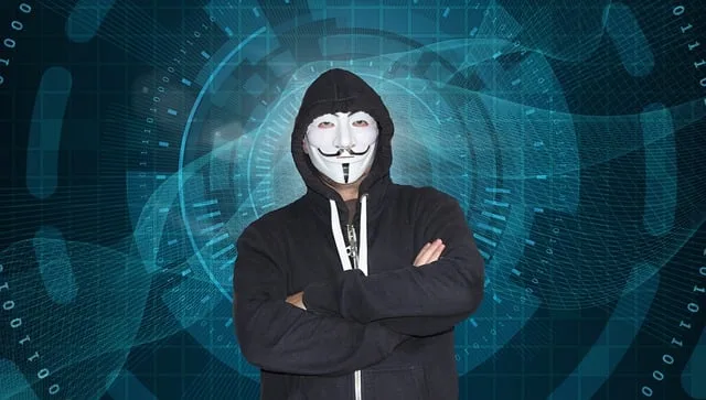 Anonymous hacker wearing facial mask in dark room